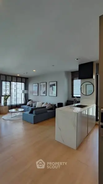 Modern open-plan living room with sleek kitchen island and city view.