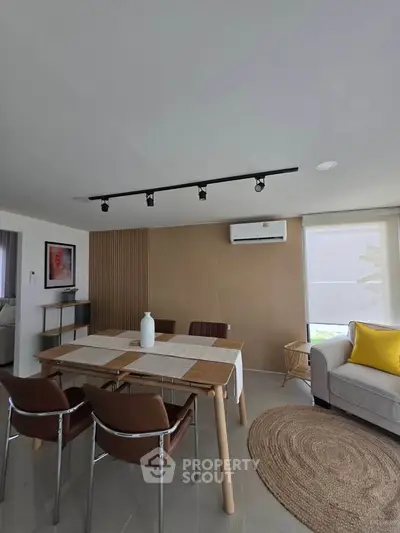 Modern living room with stylish furniture and air conditioning, featuring a cozy dining area and natural light.