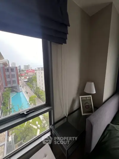 Modern bedroom with city view and pool, featuring sleek decor and natural light.