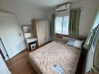 Cozy bedroom with wooden floor, air conditioning, and natural light from windows.