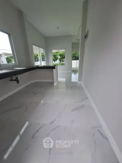 Spacious modern kitchen with marble flooring and open layout, featuring large windows for natural light.
