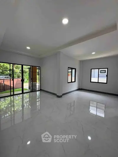 Spacious modern living room with large windows and glossy marble floors, offering abundant natural light.
