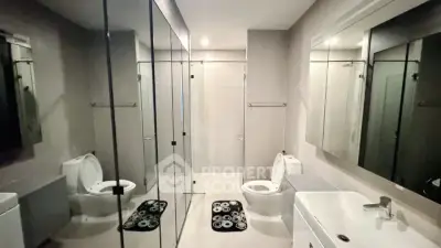 Spacious modern bathroom with dual toilets and glass shower enclosure.