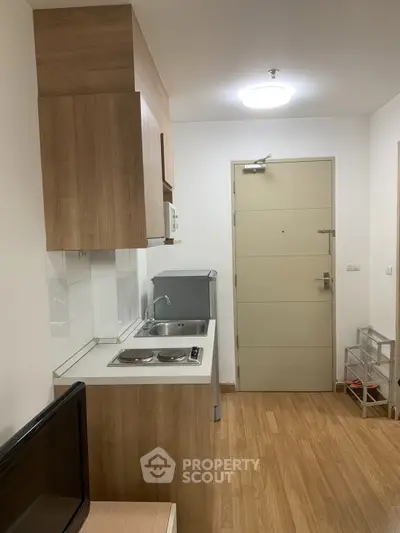 Compact kitchen with wooden cabinets and modern appliances in a cozy apartment.