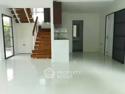 Spacious modern interior with sleek staircase and glossy white flooring