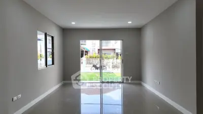 Spacious unfurnished room with large windows and sliding glass doors leading to a garden view.