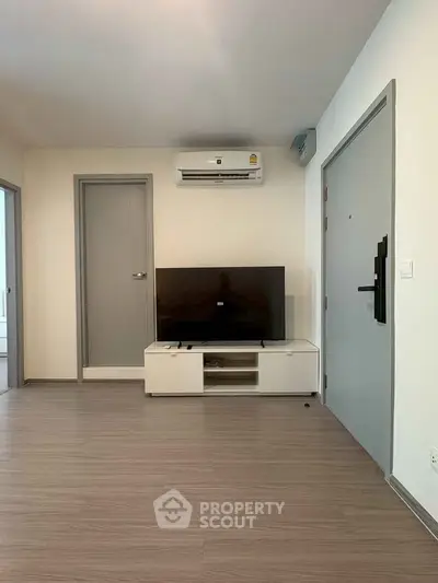 Modern living room with sleek TV setup and air conditioning in a stylish apartment.