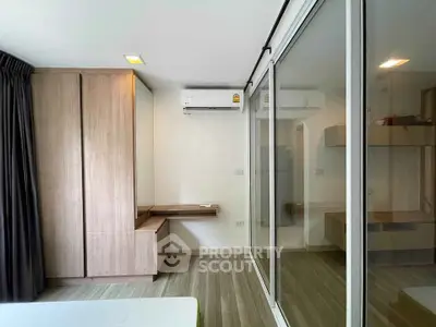 Modern bedroom with sleek wooden wardrobe and sliding glass doors in a stylish apartment.