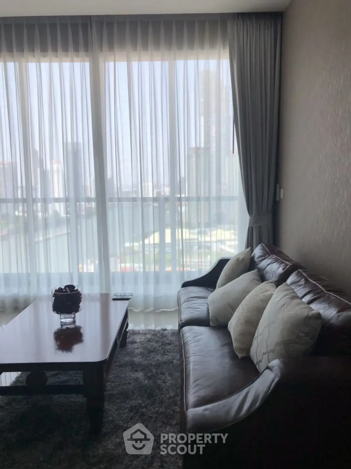 Chic living room with leather sofa and city view through large windows.