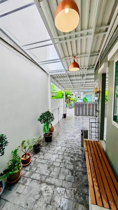 Charming outdoor patio with modern lighting and potted plants, perfect for relaxation and entertaining.