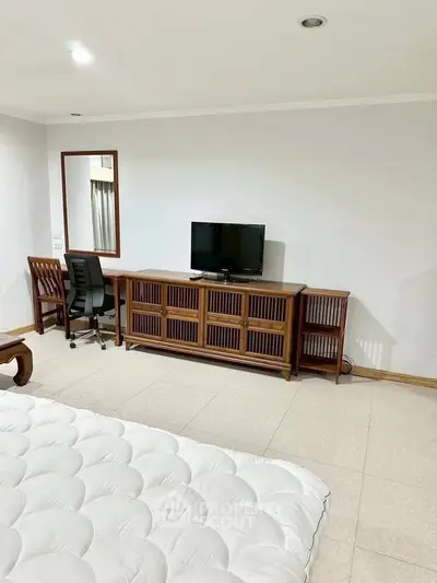 Spacious bedroom with elegant wooden furniture and modern amenities for a comfortable living experience.