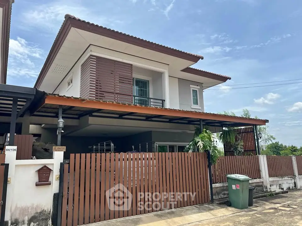 Modern two-story house with wooden accents and spacious carport in a serene neighborhood.