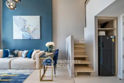 Modern living room with stylish decor and staircase, featuring a cozy dining area and sleek refrigerator.
