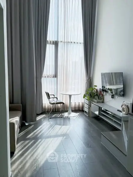 Elegant living room with high ceilings, large windows, and modern decor, perfect for urban living.