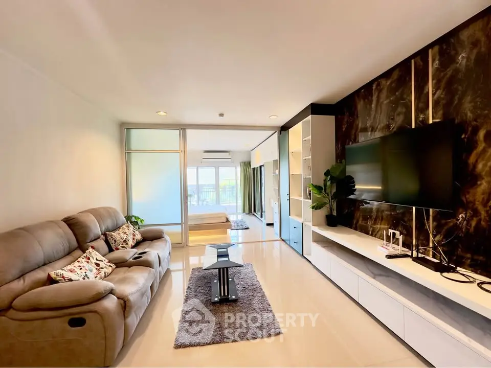 Spacious modern living room with elegant decor and large TV, perfect for relaxation.