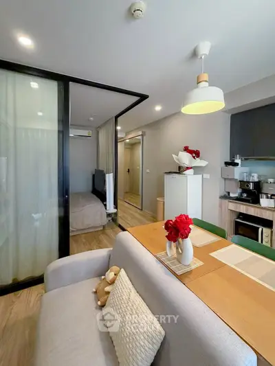 Modern open-plan living room with dining area and cozy bedroom in a stylish apartment.