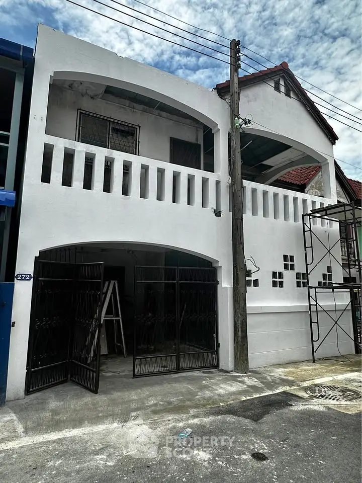 Charming two-story white building with arched balconies and gated entrance, perfect for urban living.