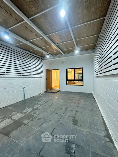 Spacious covered patio with modern lighting and tiled flooring, perfect for outdoor gatherings.