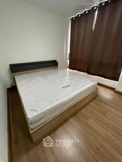 Modern bedroom with wooden flooring and large bed near window with dark curtains.