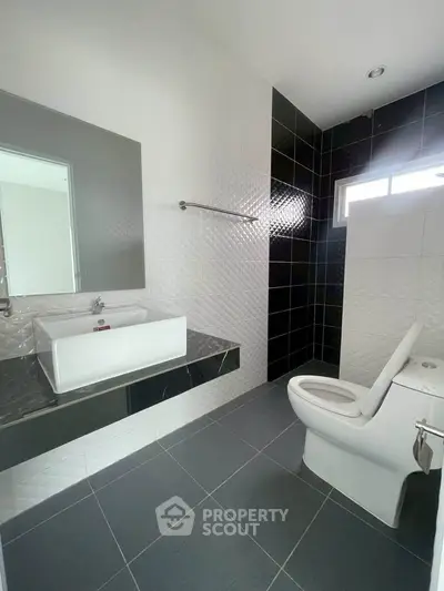 Modern bathroom with sleek black and white tiles and contemporary fixtures.
