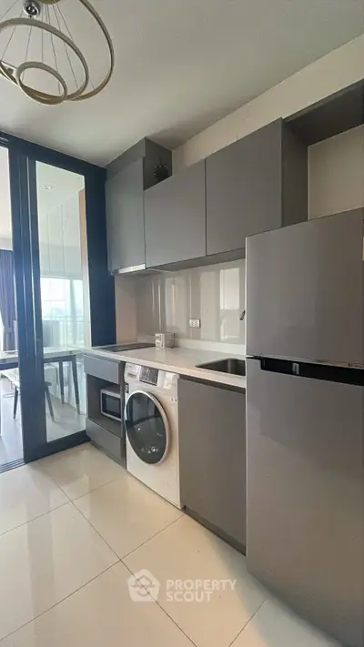Modern kitchen with sleek cabinets, integrated appliances, and washing machine in a stylish apartment.