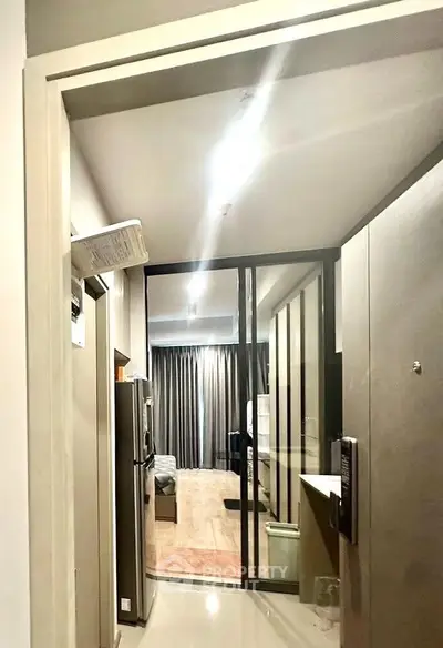Modern apartment entrance with sleek design and glass partition leading to living area.