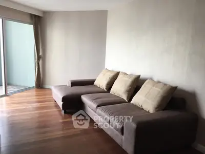 Spacious living room with modern brown sofa and wooden flooring, perfect for relaxation.
