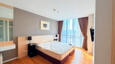 Spacious bedroom with large window and wooden flooring in modern apartment.