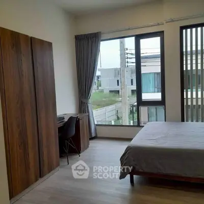 Spacious bedroom with large windows and modern furnishings in a contemporary home.