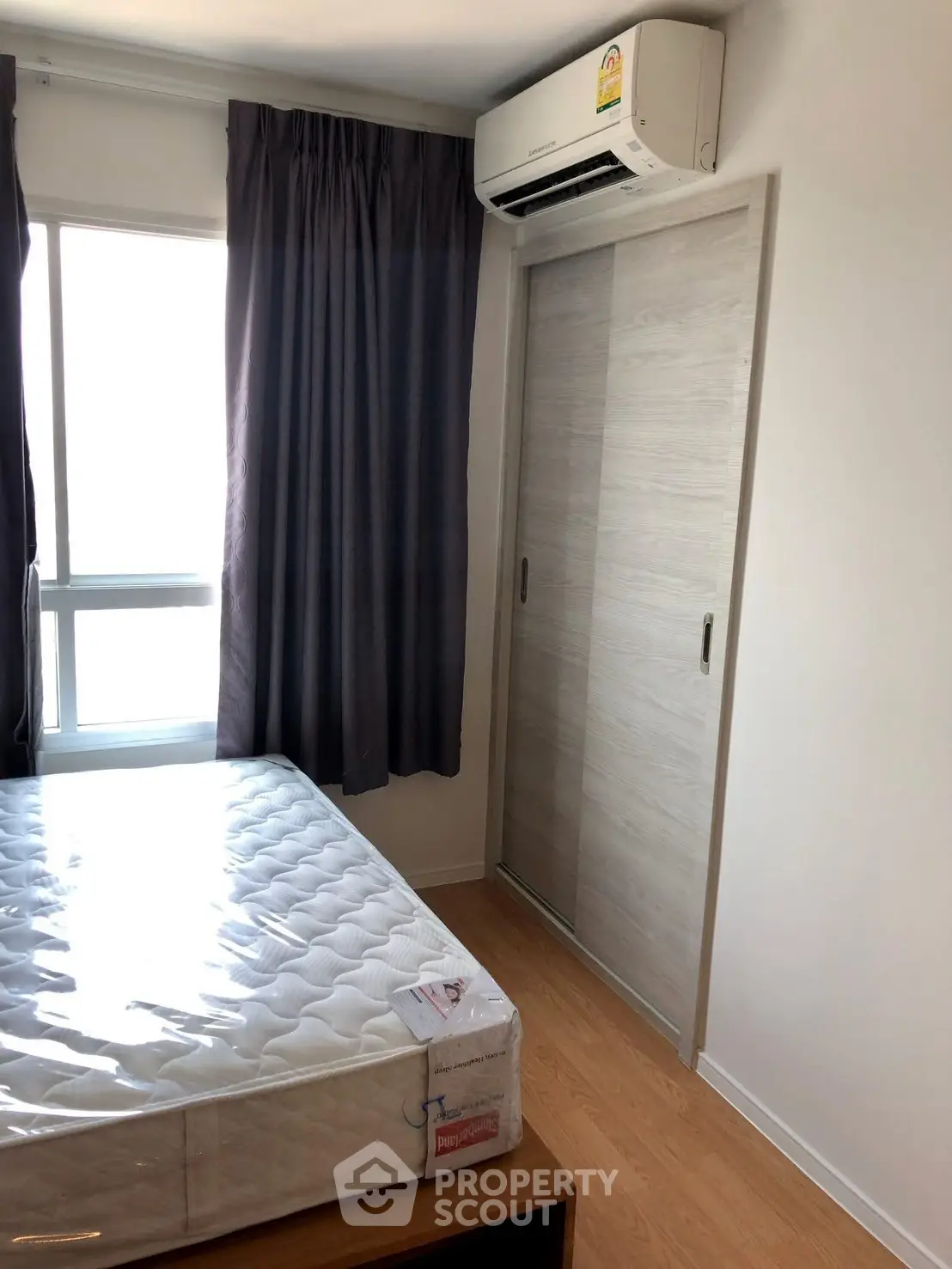 Cozy bedroom with natural light, featuring a sliding closet and air conditioning.
