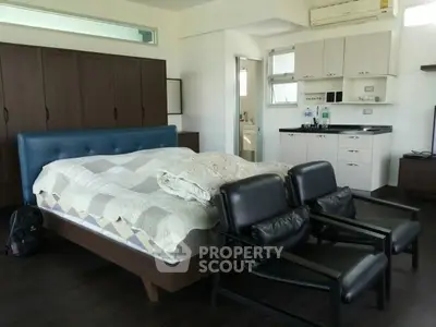 Spacious bedroom with modern furniture and kitchenette, ideal for urban living