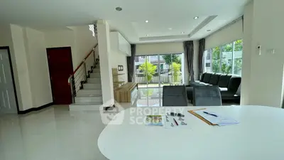 Spacious modern living room with large windows and stylish staircase