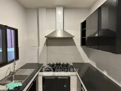 Modern kitchen with sleek black cabinets and gas stove, perfect for culinary enthusiasts.