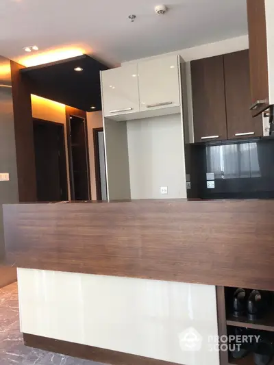 Sleek modern kitchen with dark wood cabinetry and a contrasting white breakfast bar, offering a stylish and functional space for culinary enthusiasts.