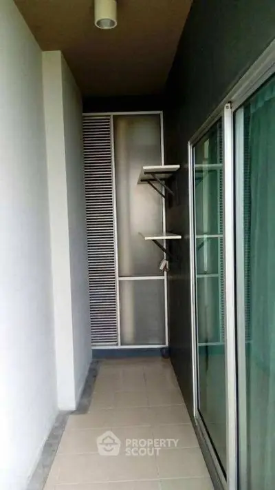 Narrow balcony with sliding glass doors and shelving, ideal for compact outdoor space.