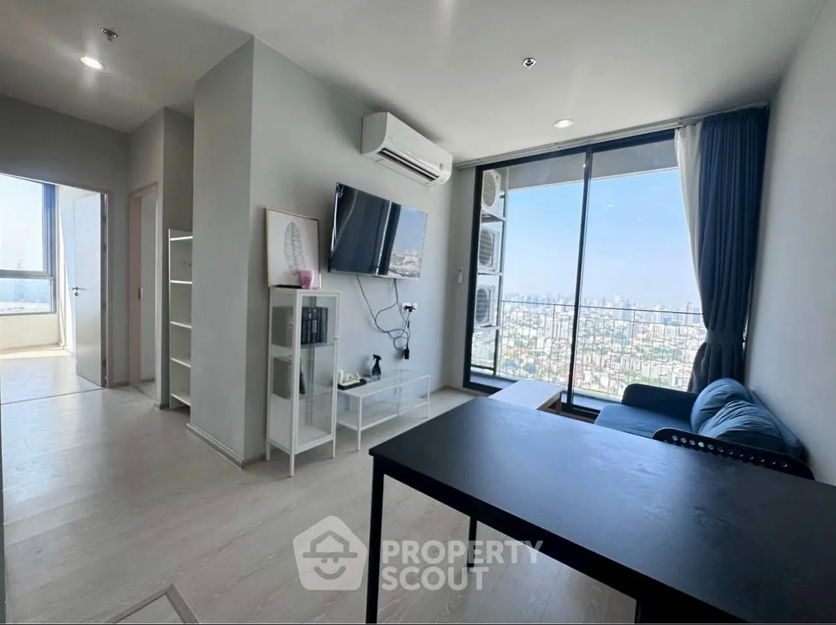 Modern living room with city view, featuring sleek furniture and large windows for natural light.