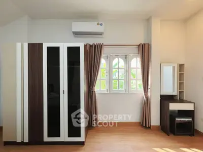 Bright bedroom with modern wardrobe and vanity set, featuring natural light through elegant window curtains.