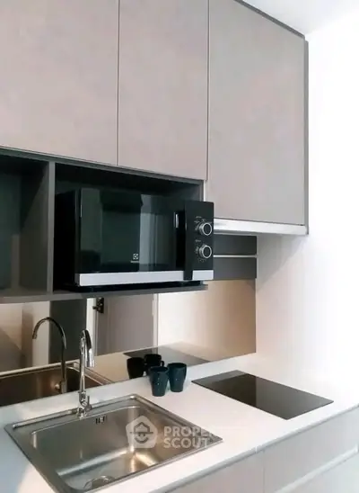 Modern kitchen with sleek cabinetry, built-in microwave, and induction cooktop.
