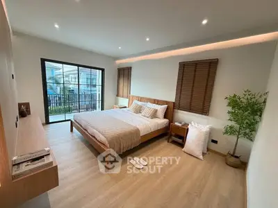 Spacious modern bedroom with wooden furniture and balcony access, perfect for relaxation.