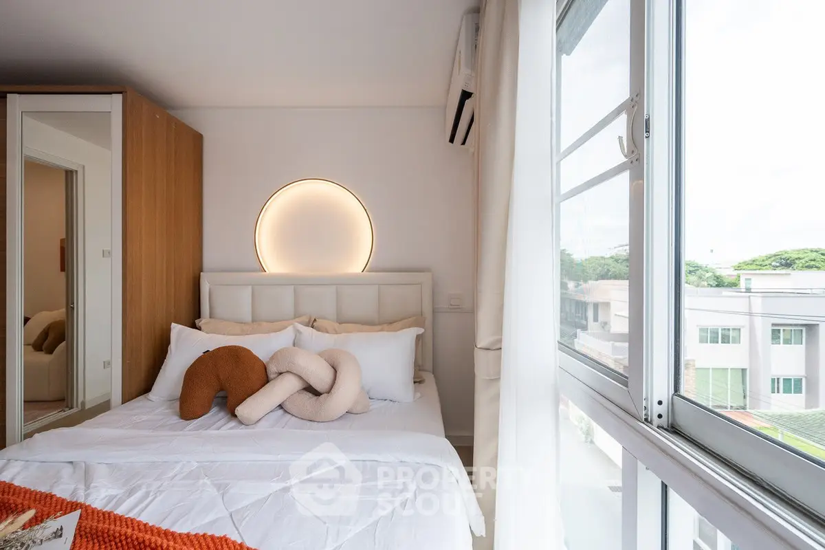 Modern bedroom with large window and stylish decor, offering a bright and inviting atmosphere.