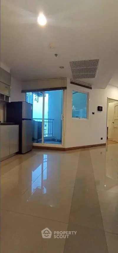 Spacious modern living room with balcony access and sleek tiled flooring.