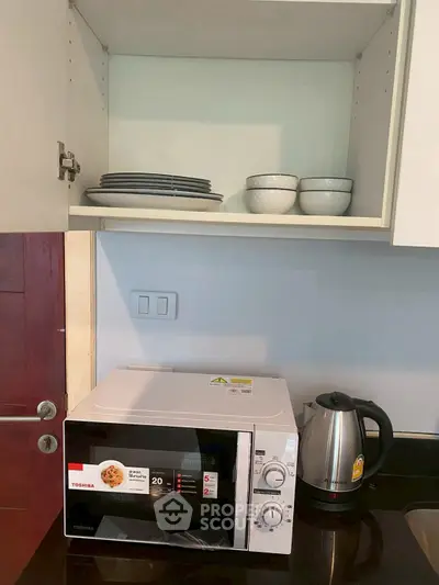 Modern kitchen with microwave and kettle under neatly organized cabinet