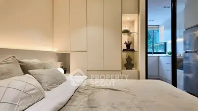 Modern bedroom with elegant decor and view into sleek kitchen area.