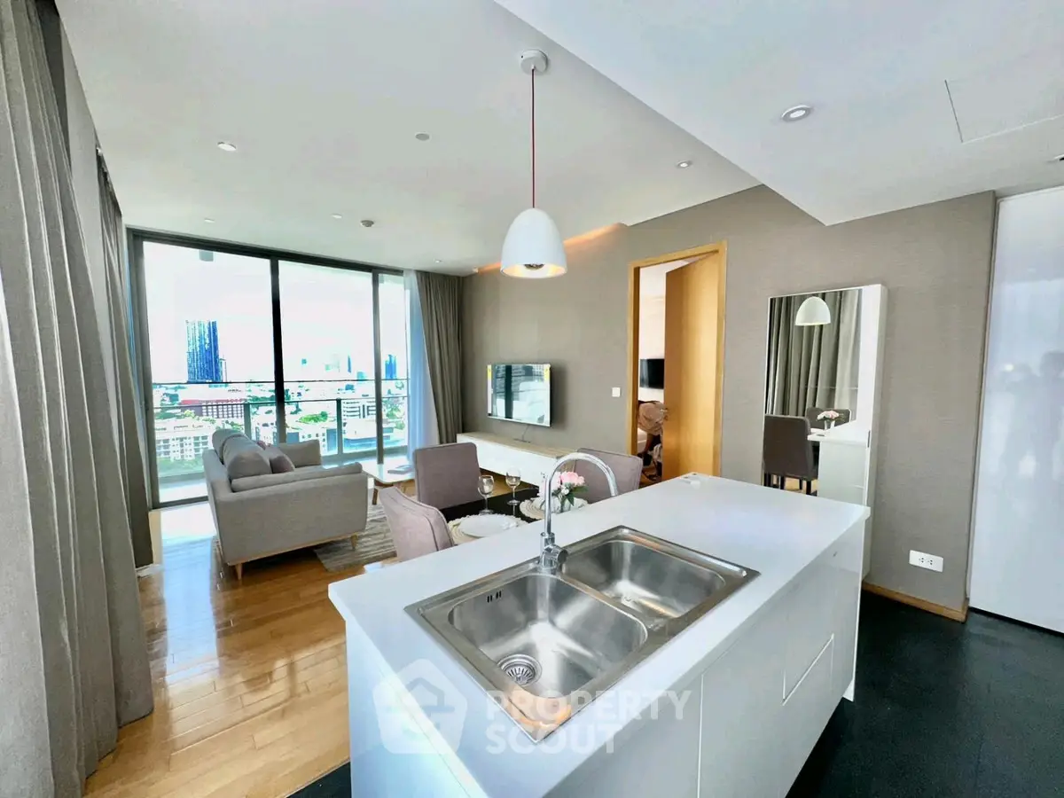 Modern open-plan living room with city view, featuring sleek kitchen island and stylish decor.