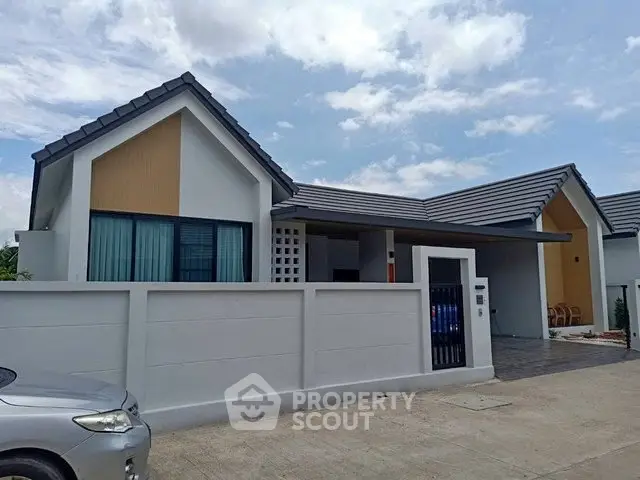 Modern single-story house with sleek design and spacious driveway under a clear blue sky.
