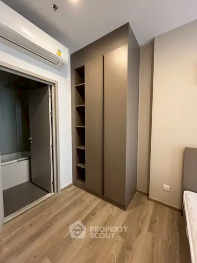 Modern bedroom with built-in wardrobe and air conditioning, featuring sleek wooden flooring.