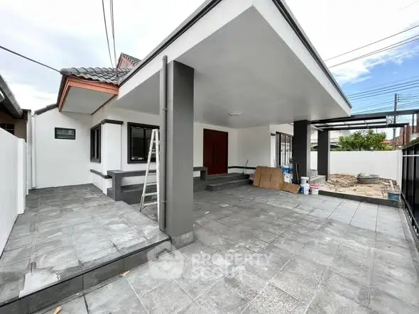 Modern renovated home exterior with spacious tiled driveway and contemporary design.