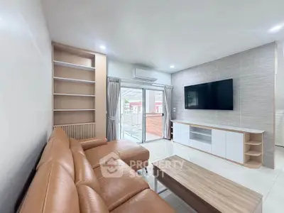 Modern living room with leather sofa, built-in shelves, and large TV, featuring a bright and airy design.
