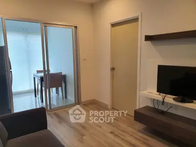 Modern living room with sleek TV setup and sliding glass doors leading to dining area.