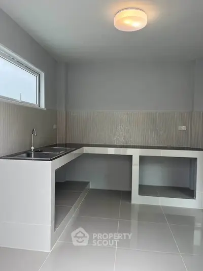 Modern minimalist kitchen with sleek countertops and ample natural light.